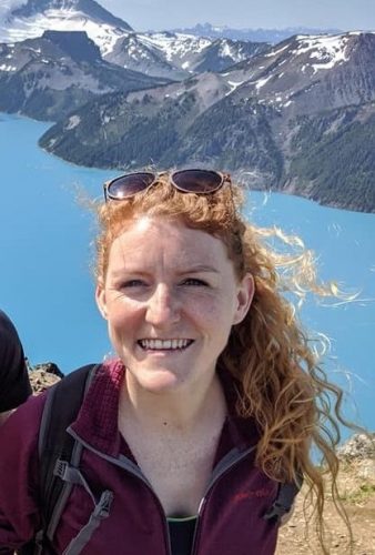 Jules standing in front of a mountain and lake