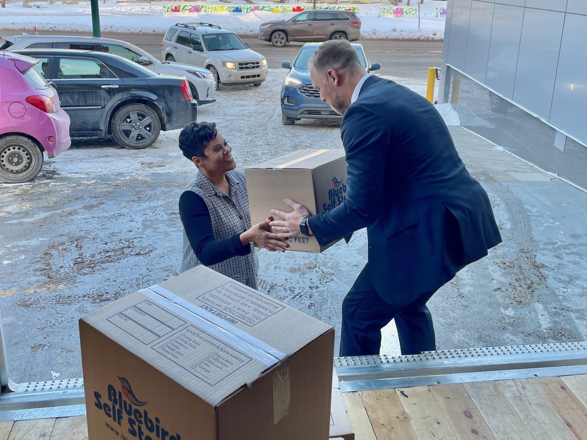 The Honourable Marci Ien, Minister for Women and Gender Equality and Youth, handing a moving box to Shelter Movers' Executive Director Marc Hull-Jacquin.